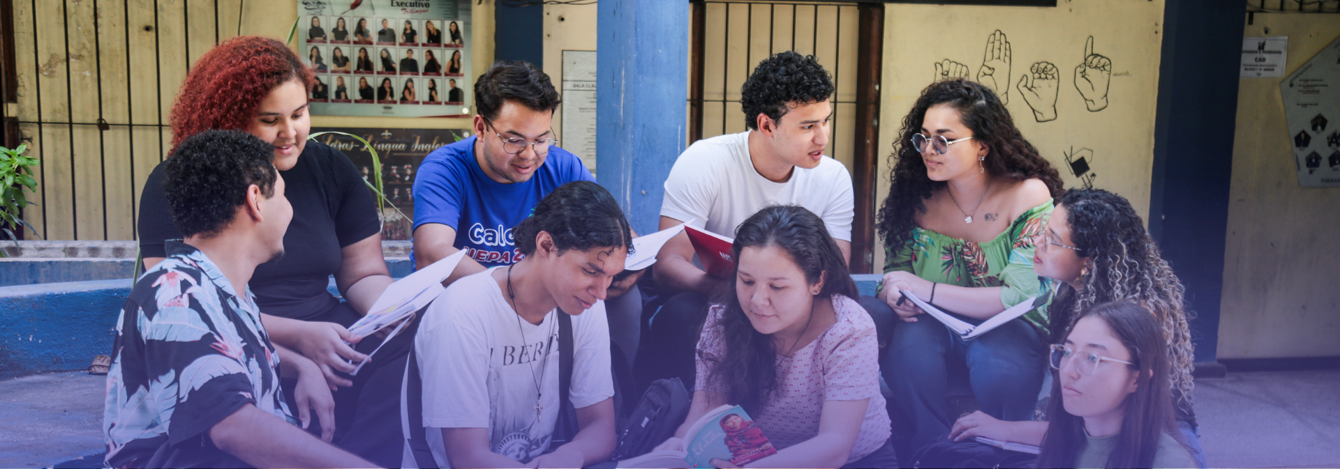 Grupo de estudantes reunidos em um espaço acadêmico, sentados em roda e interagindo com livros, cadernos e materiais de estudo, em um momento de convivência, troca de ideias e aprendizado coletivo.