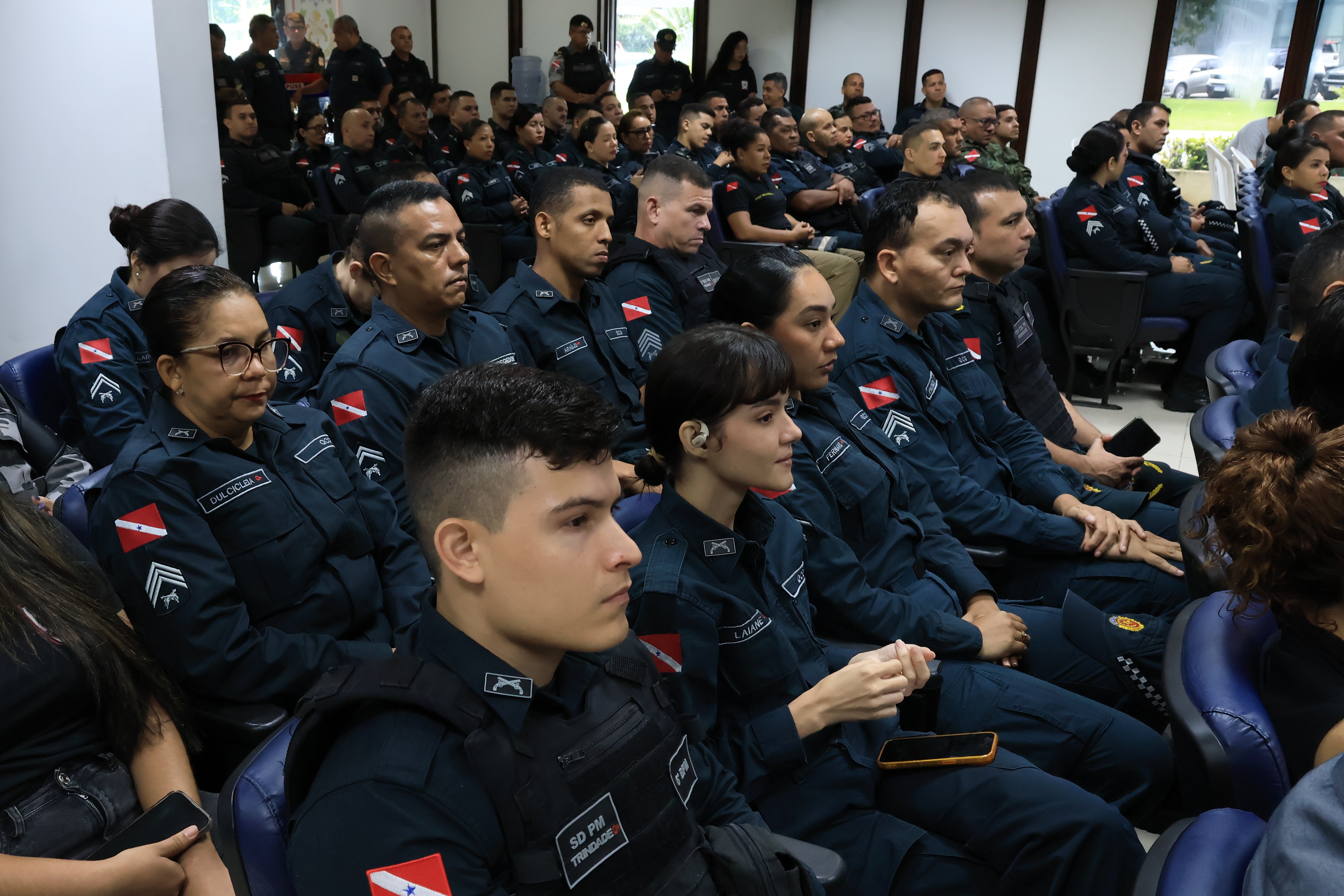 A imagem mostra o público presente em uma cerimônia da Polícia Militar do Pará. Os participantes, em sua maioria policiais fardados, estão sentados em atenção, demonstrando concentração e envolvimento com o evento. 