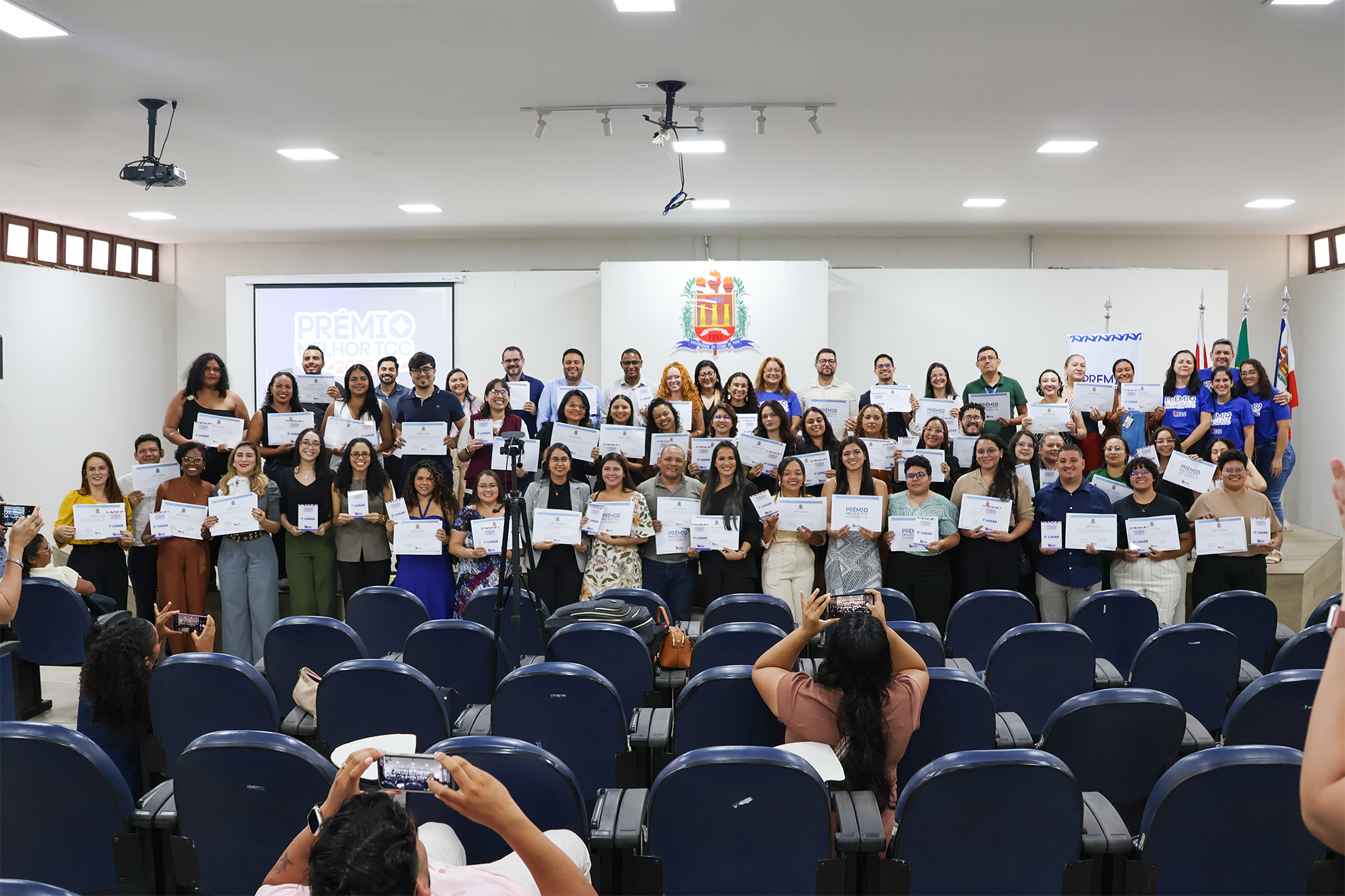 Em um auditório, alunos da Uepa posam para foto com certificados do Prêmio Melhor TCC em mãos 