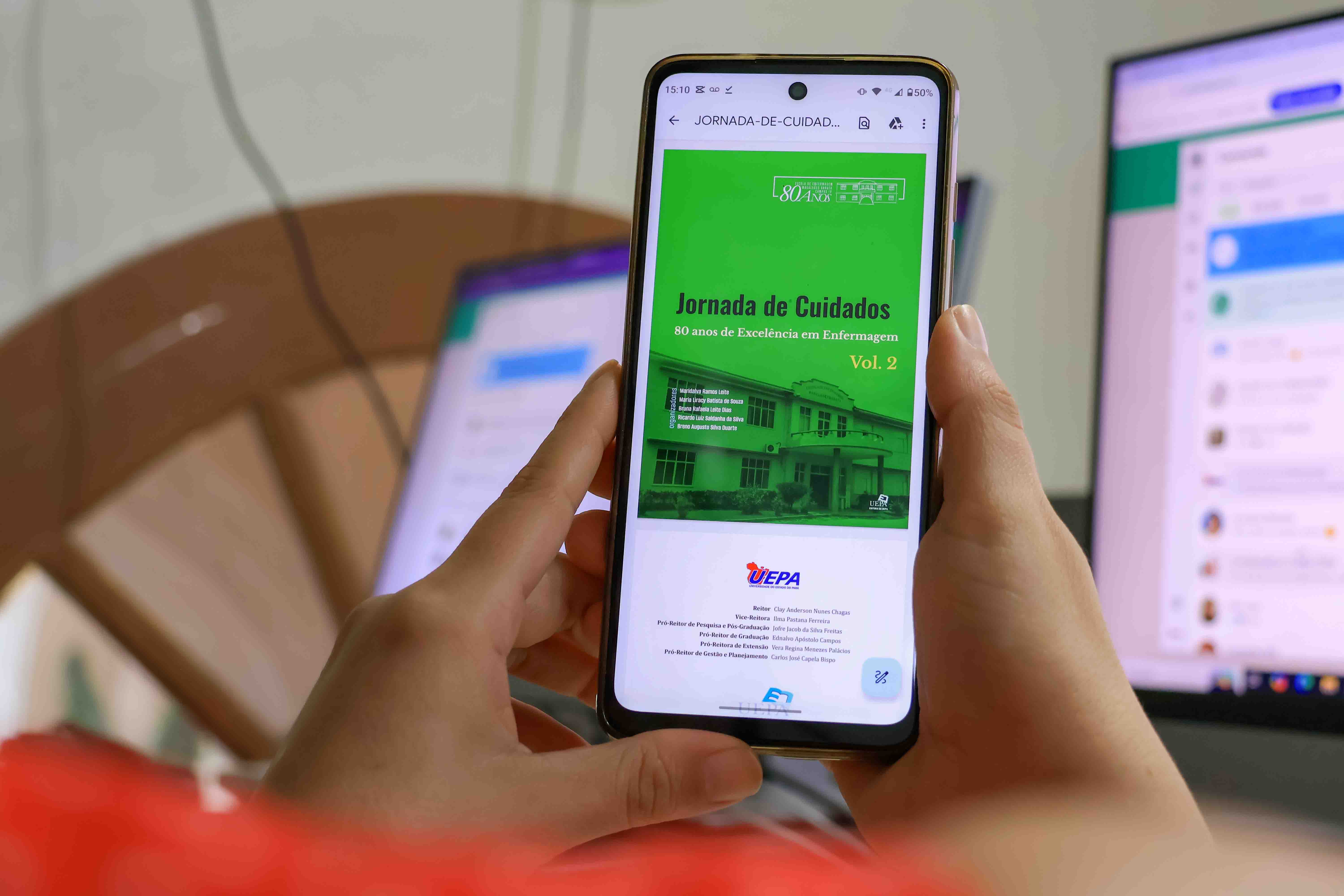 A imagem mostra uma pessoa segurando um smartphone com as duas mãos, exibindo na tela uma publicação intitulada "Jornada de Cuidados: 80 anos de Excelência em Enfermagem, Vol. 2". O design da capa é verde, com uma foto do prédio da Escola de Enfermagem Magalhães Barata na parte inferior. O logo da Universidade do Estado do Pará (Uepa) aparece na parte inferior da tela.