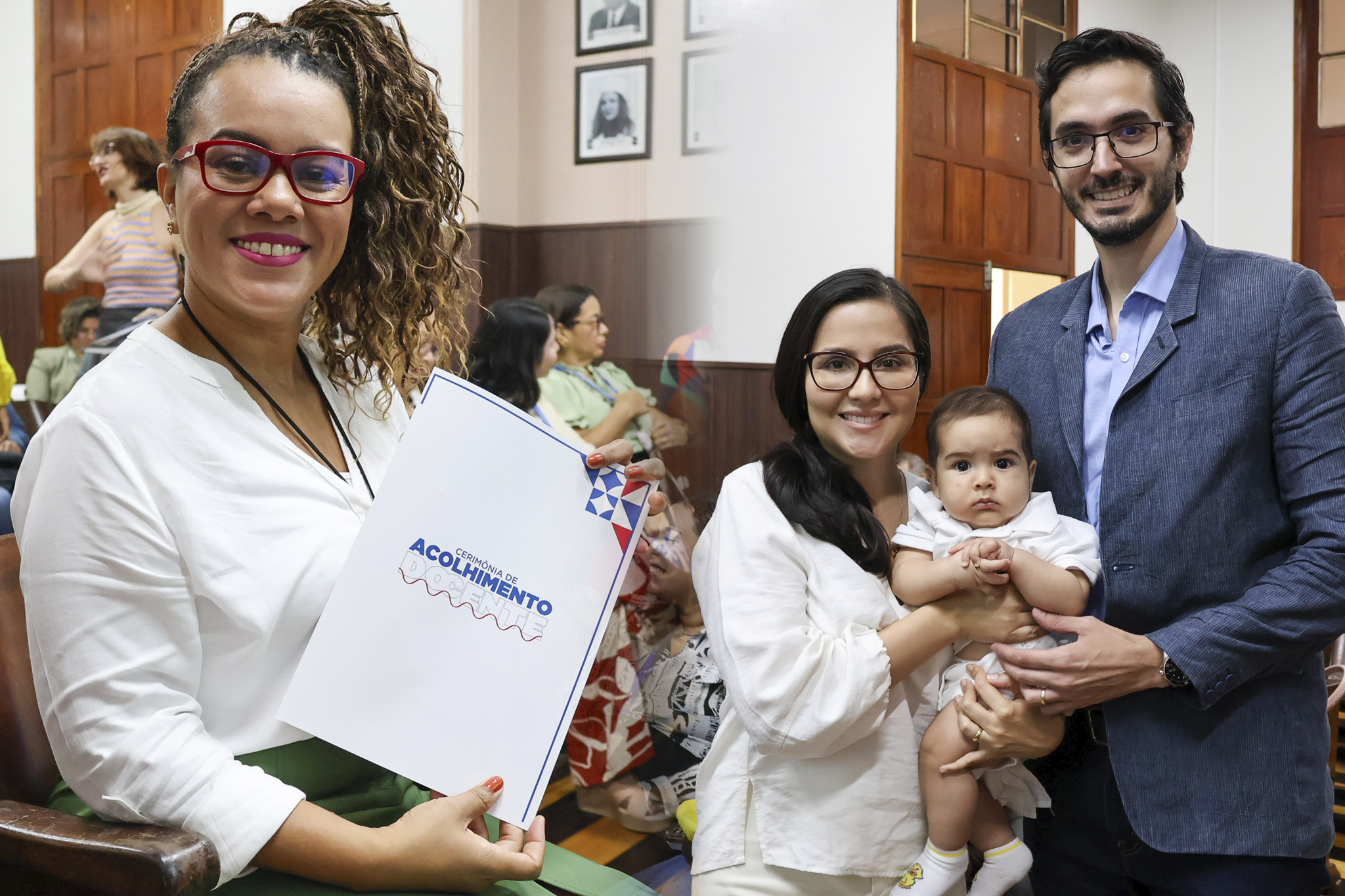 Uma mulher segura uma pasta com a inscrição “Cerimônia de Acolhimento” e posa ao lado de um casal que carrega um bebê, em um ambiente interno com outras pessoas sentadas ao fundo, sugerindo um evento institucional ou comunitário