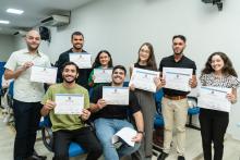 Grupo menor de alunos posando juntos, cada um mostrando seu certificado com sorrisos de celebração.